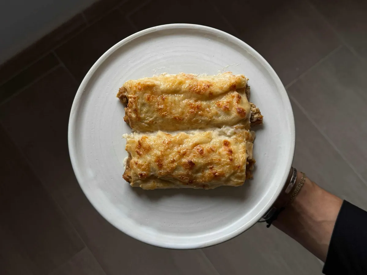 Manos enrollando canelones caseros